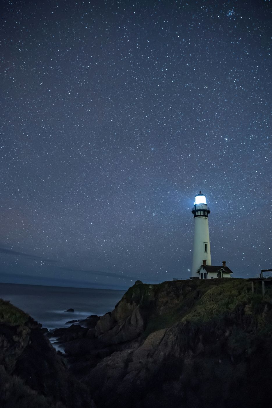 A lighthouse under a star filled sky