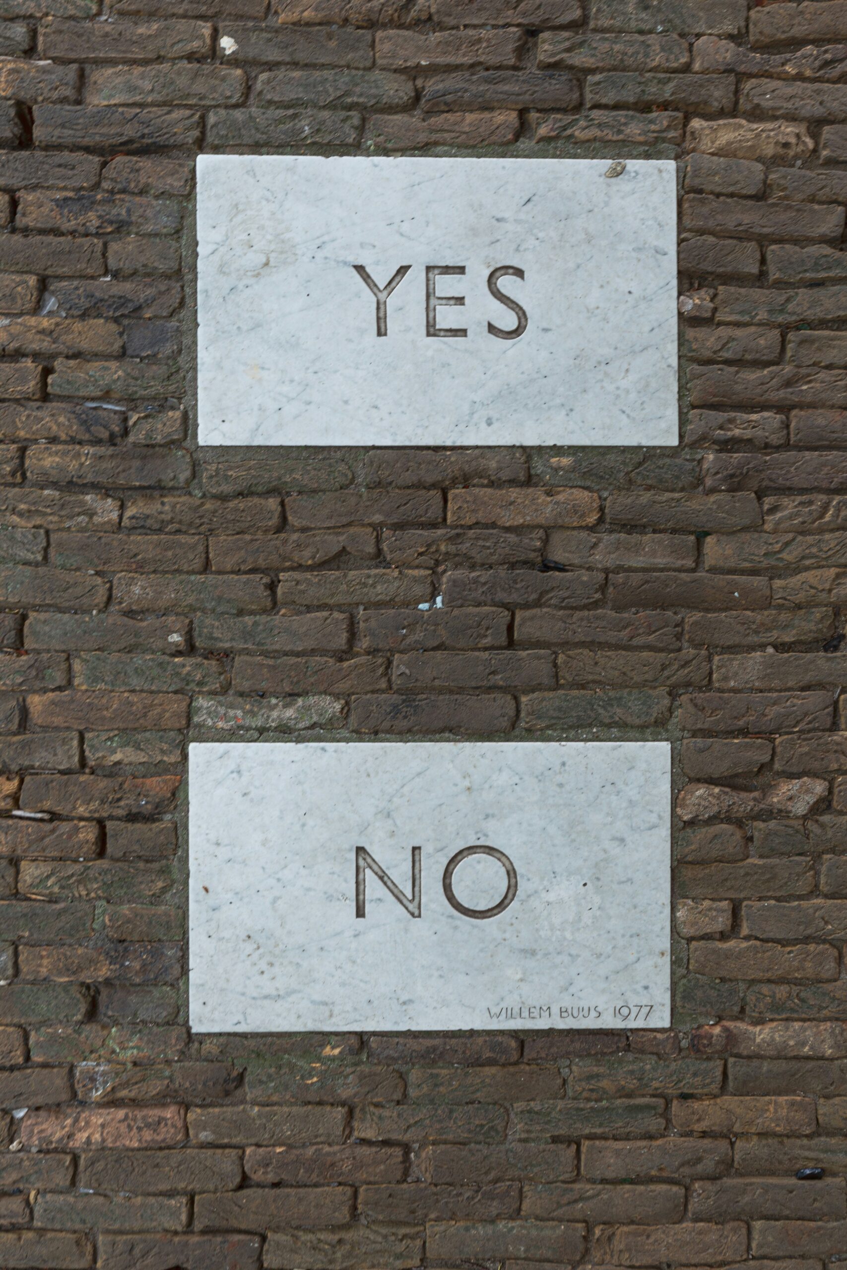 Two marble blocks in a brick wall, top: yes, bottom: no