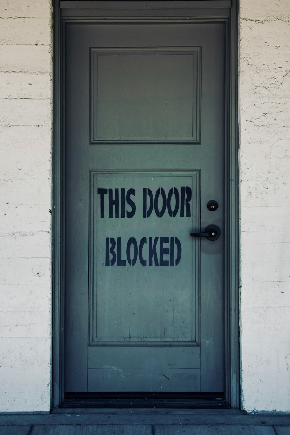 A blue door with This Door Is Blocked stenciled on it