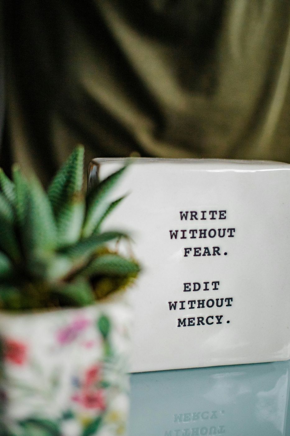 A ceramic tile with Write Without Fear, Edit Without Mercy etched on it