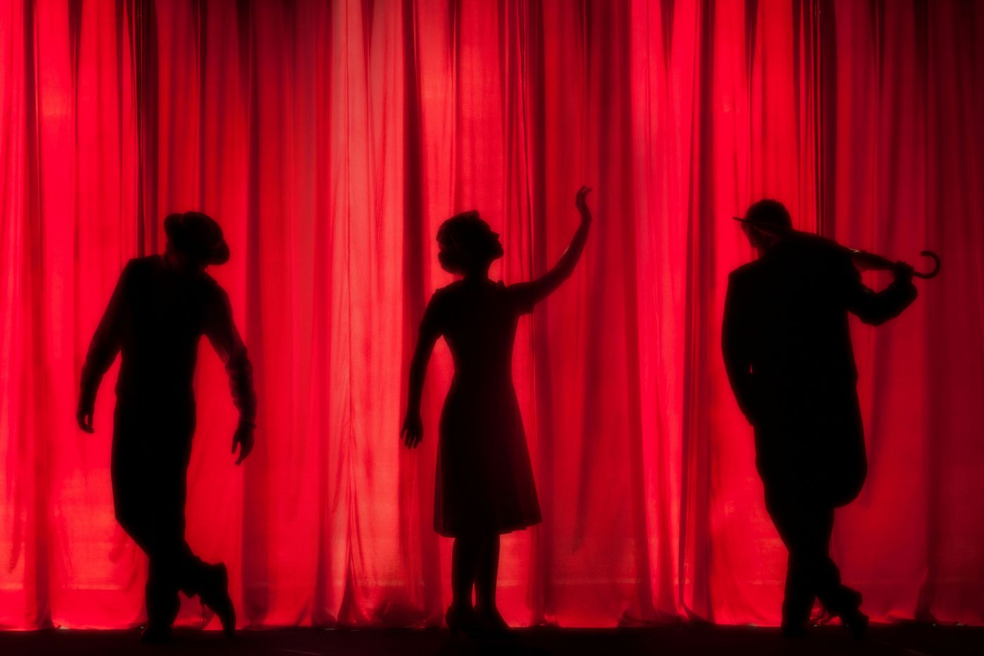 The silhouettes of 3 performers on stage.