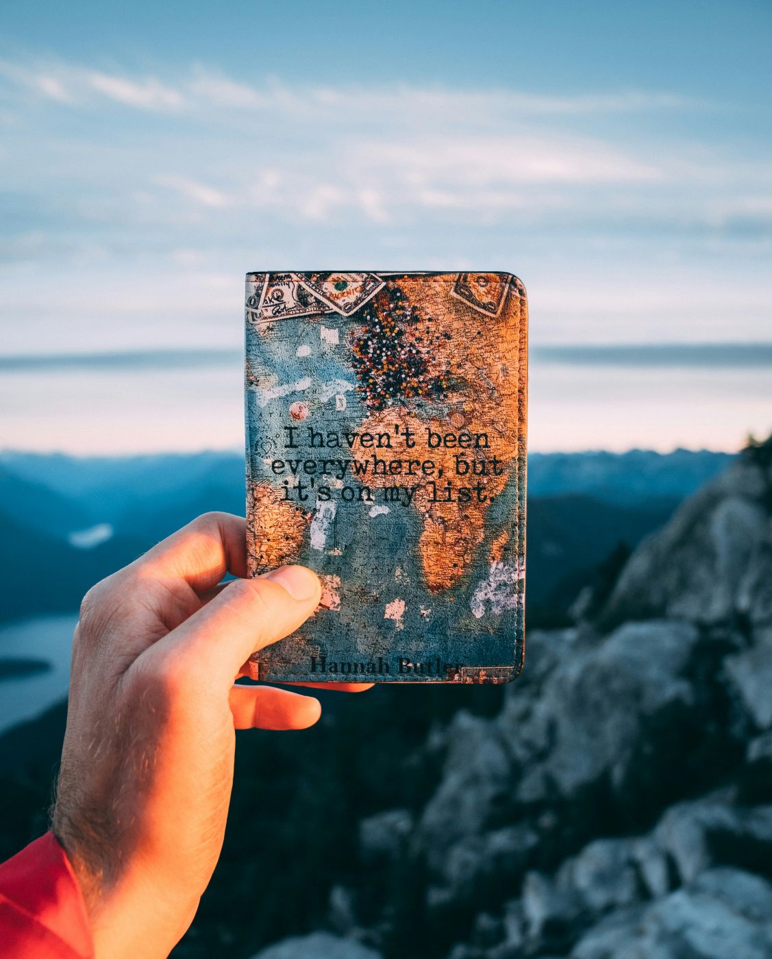 A person holding a notebook with I haven't been everywhere, but it's on my list on the cover