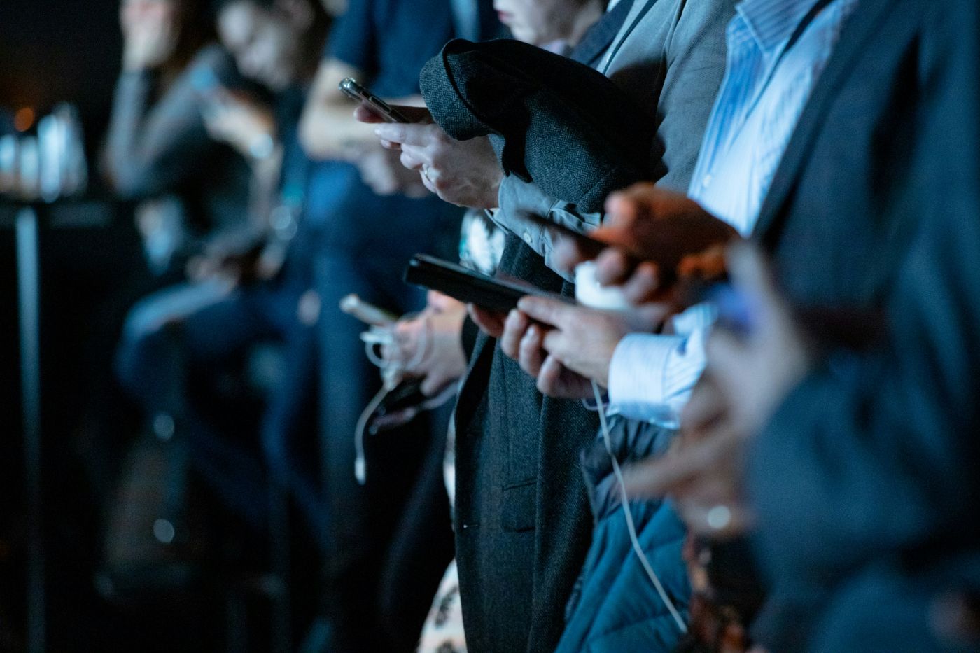 Many people standing on a train platform all looking at their phones