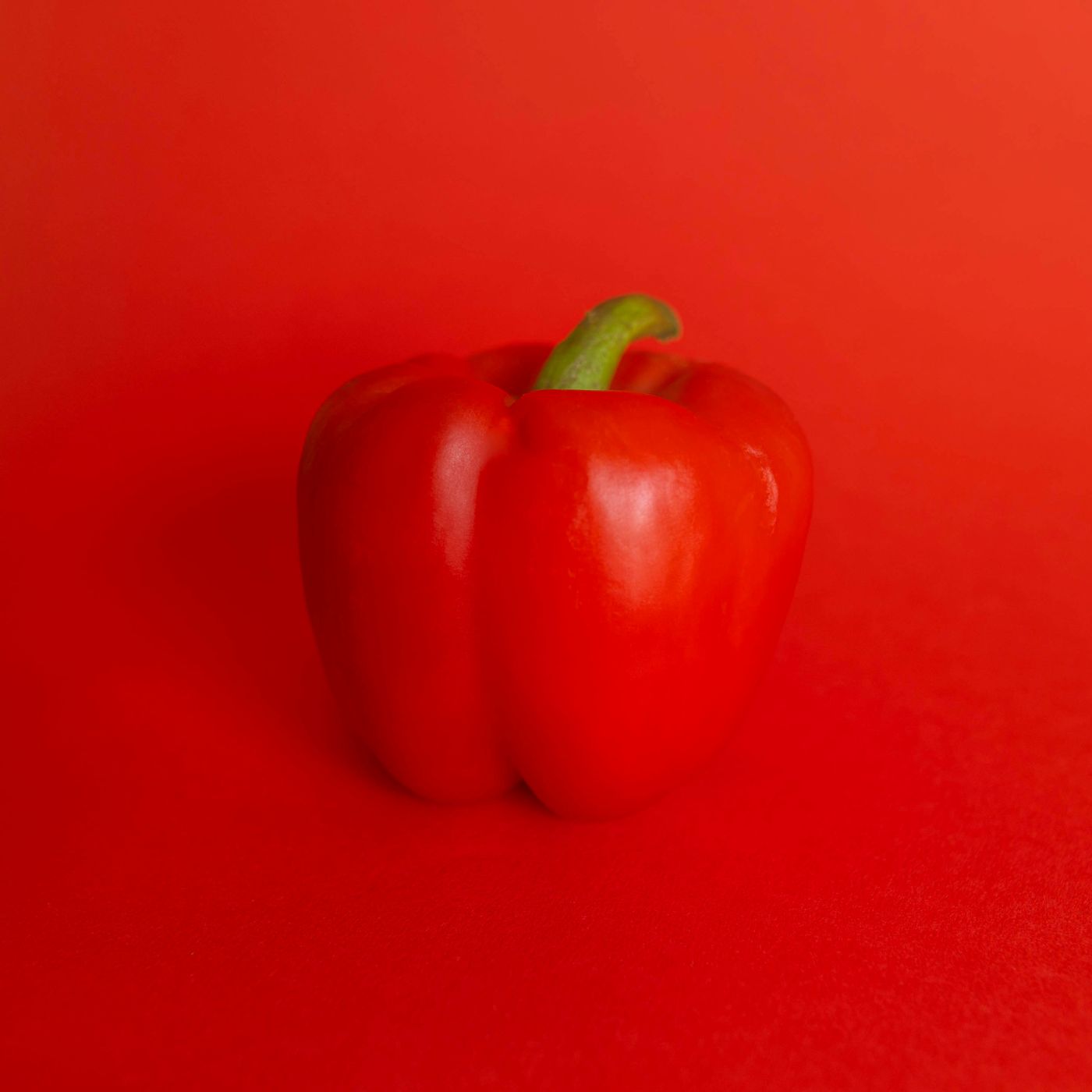 A red bell pepper against a red background