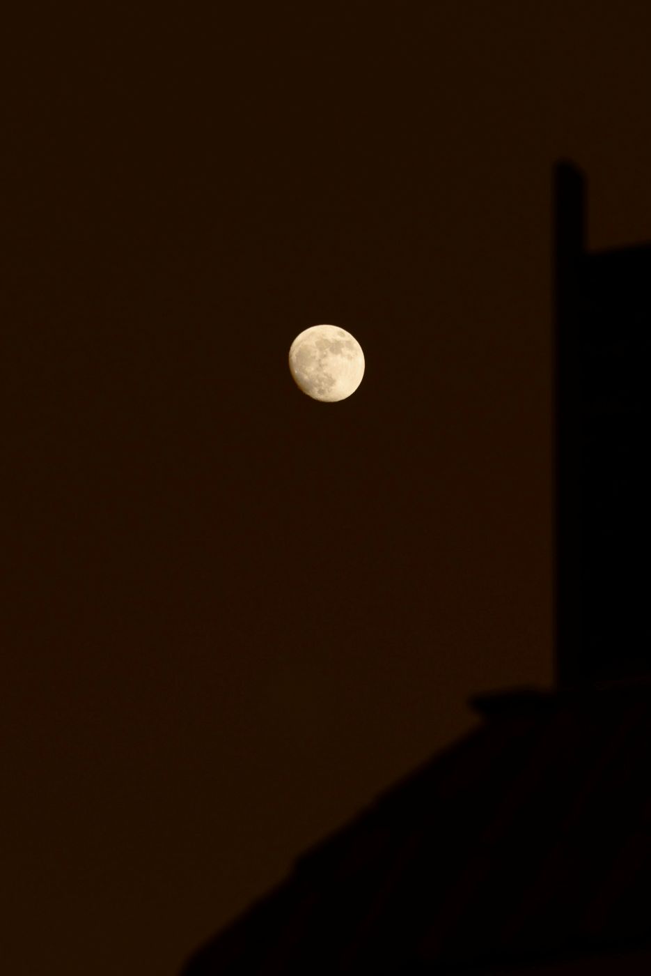 The moon high above a silhouetted building