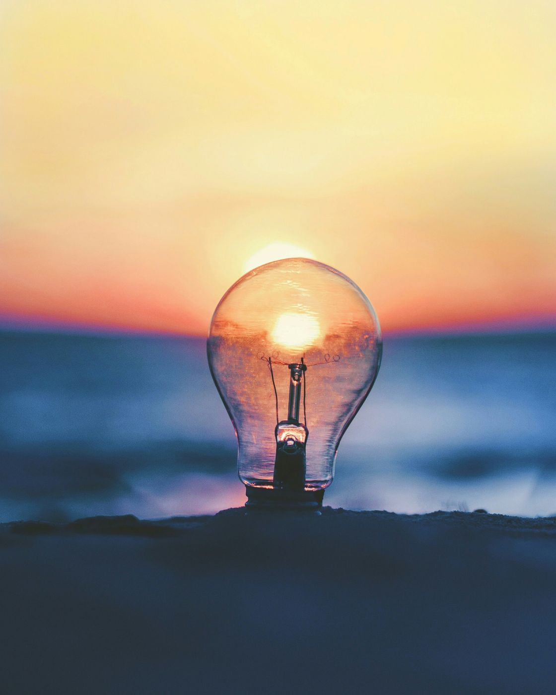 A lightbulb buried in sad with the sunset caught in it