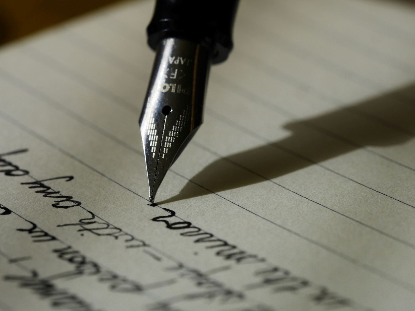 A close up of a pen nib writing on lined paper