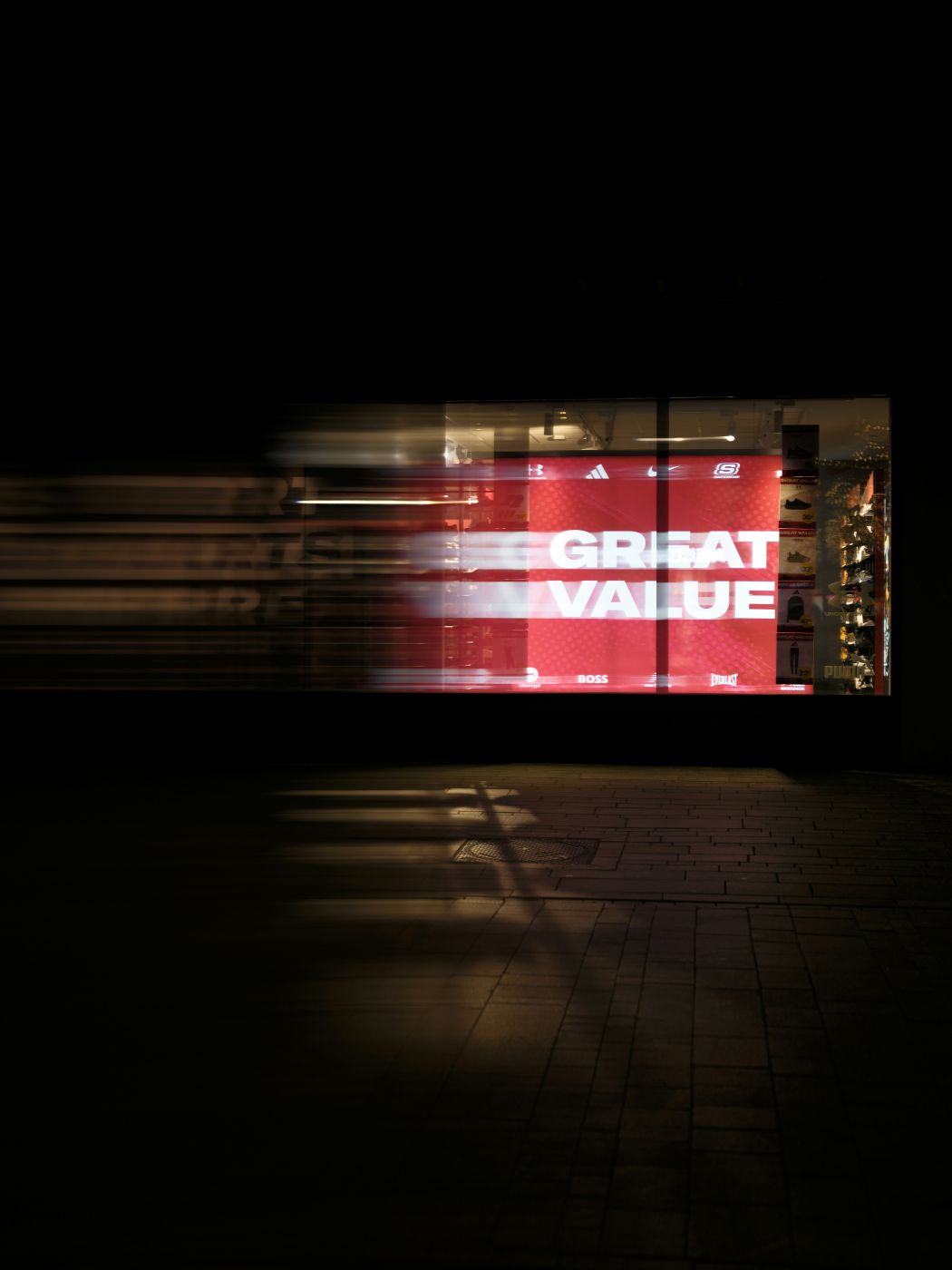 A sign in a storefront on a dark street reading GREAT VALUE