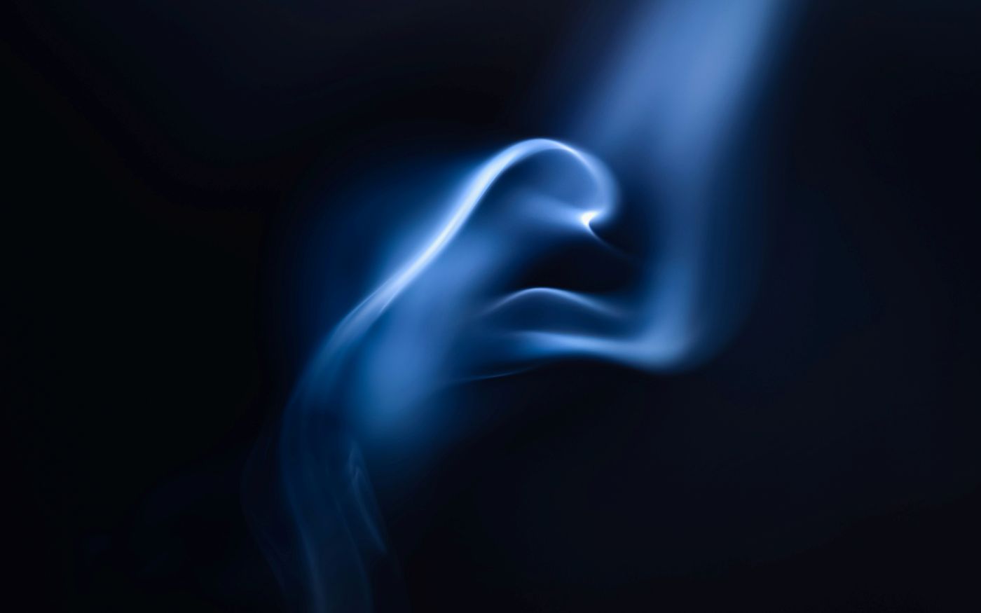 Blue and white whisps of smoke against a black background