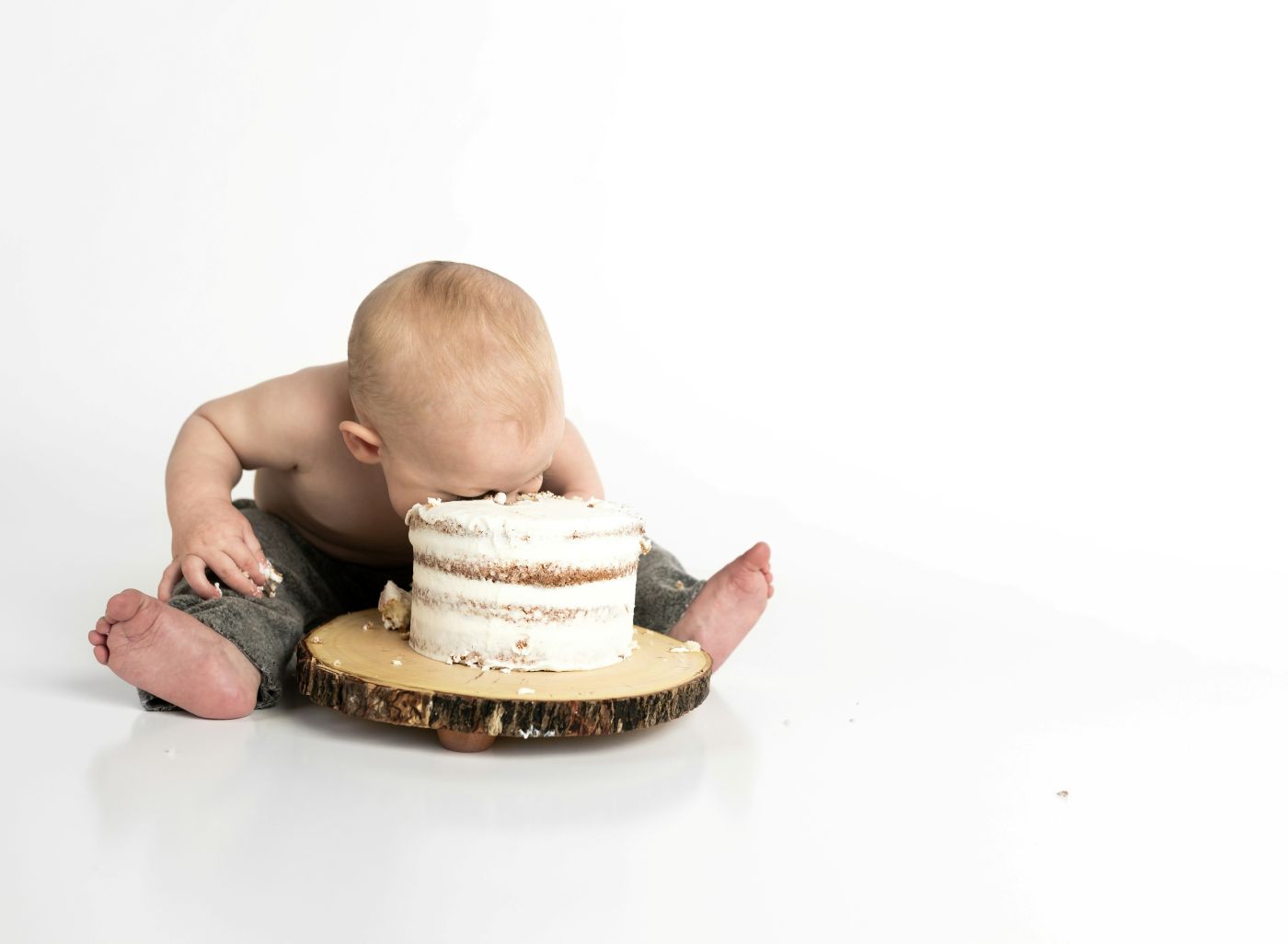 A baby sticking its face in a whole cake
