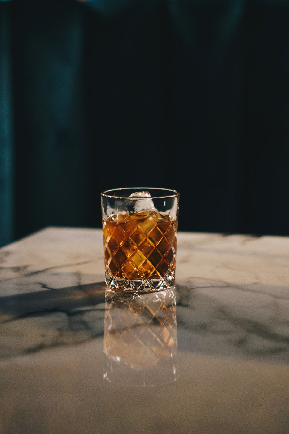 a glass of bourbon on a marble table