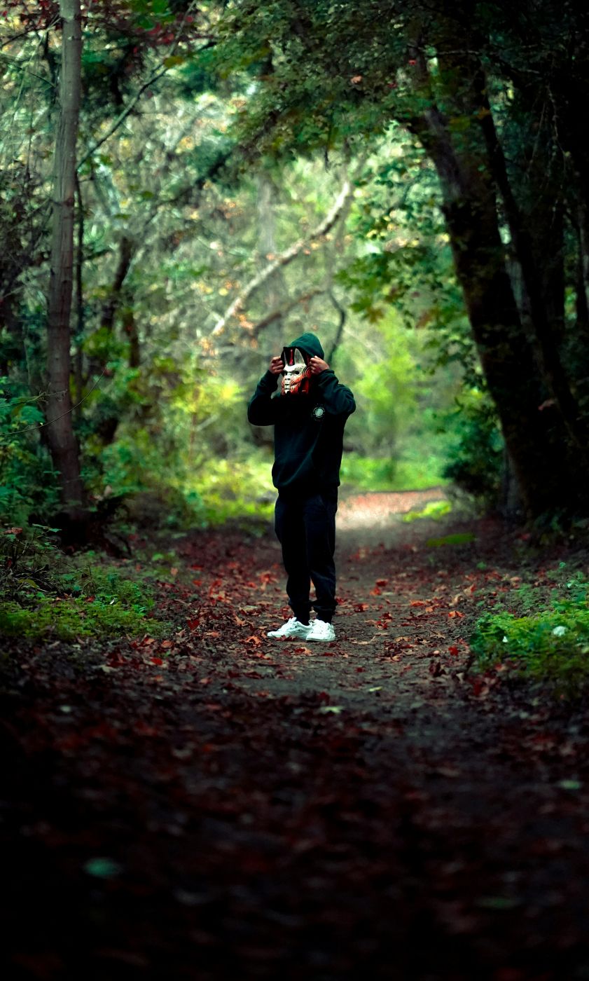Person putting on a scary Chinese mask standing in the woods