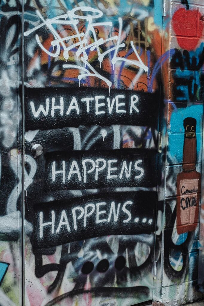 Graffiti on a wall reading whatever happens happens ...