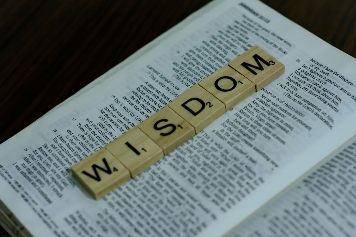 An open Bible with Scrabble tiles on ti spelling out wisdom