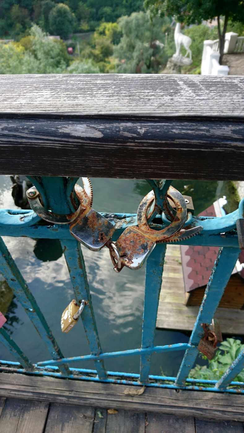 A pair of rusted handcuffs attached to a fence