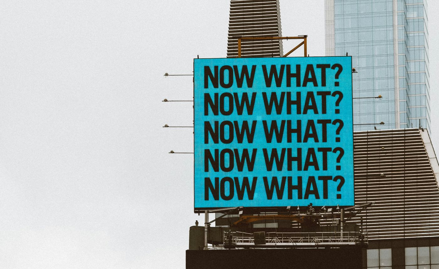 BIllboard with ablue background and the words Now What? written five times