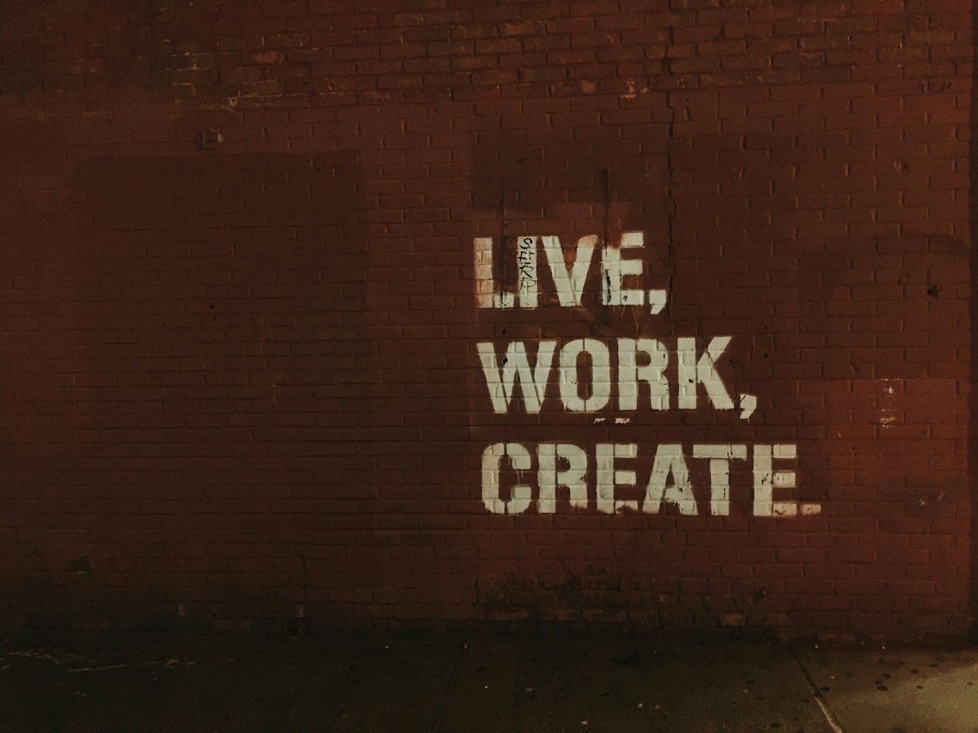 Red wall with Live, Work, Create stenciled on it in white