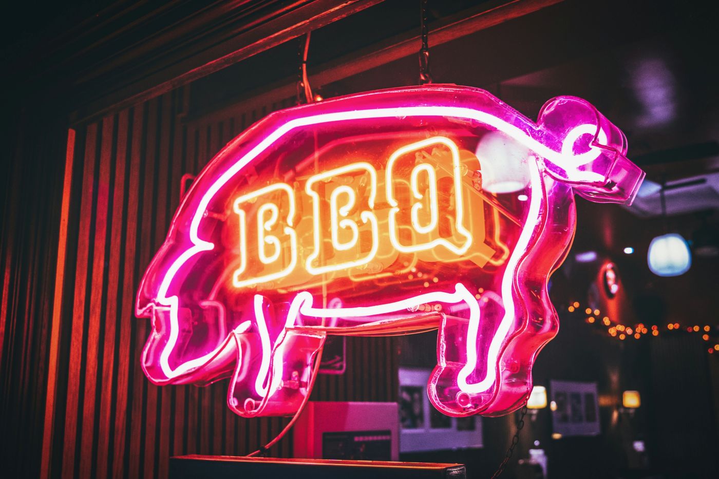 Pink Neon sign in the shape of a pig with the letters BBQ inside the pig's frame