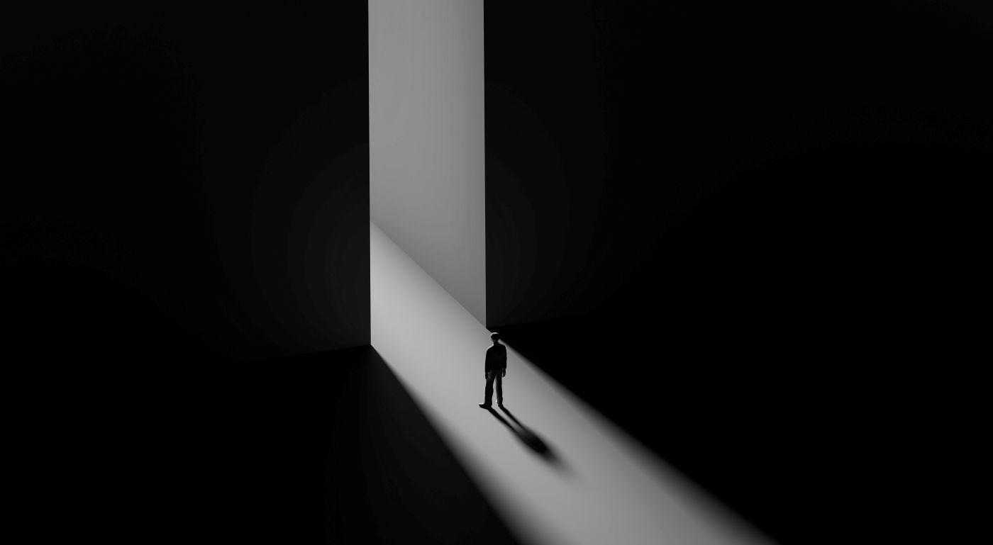 A man standing in the light coming through between two walls