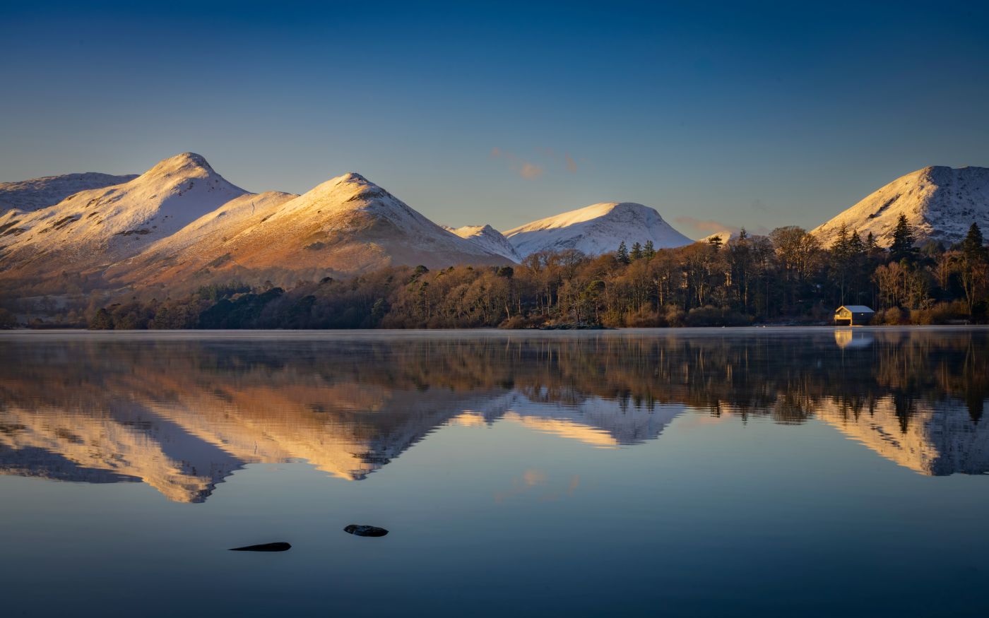 Mountains and a cabin perfectly reflected in a lake