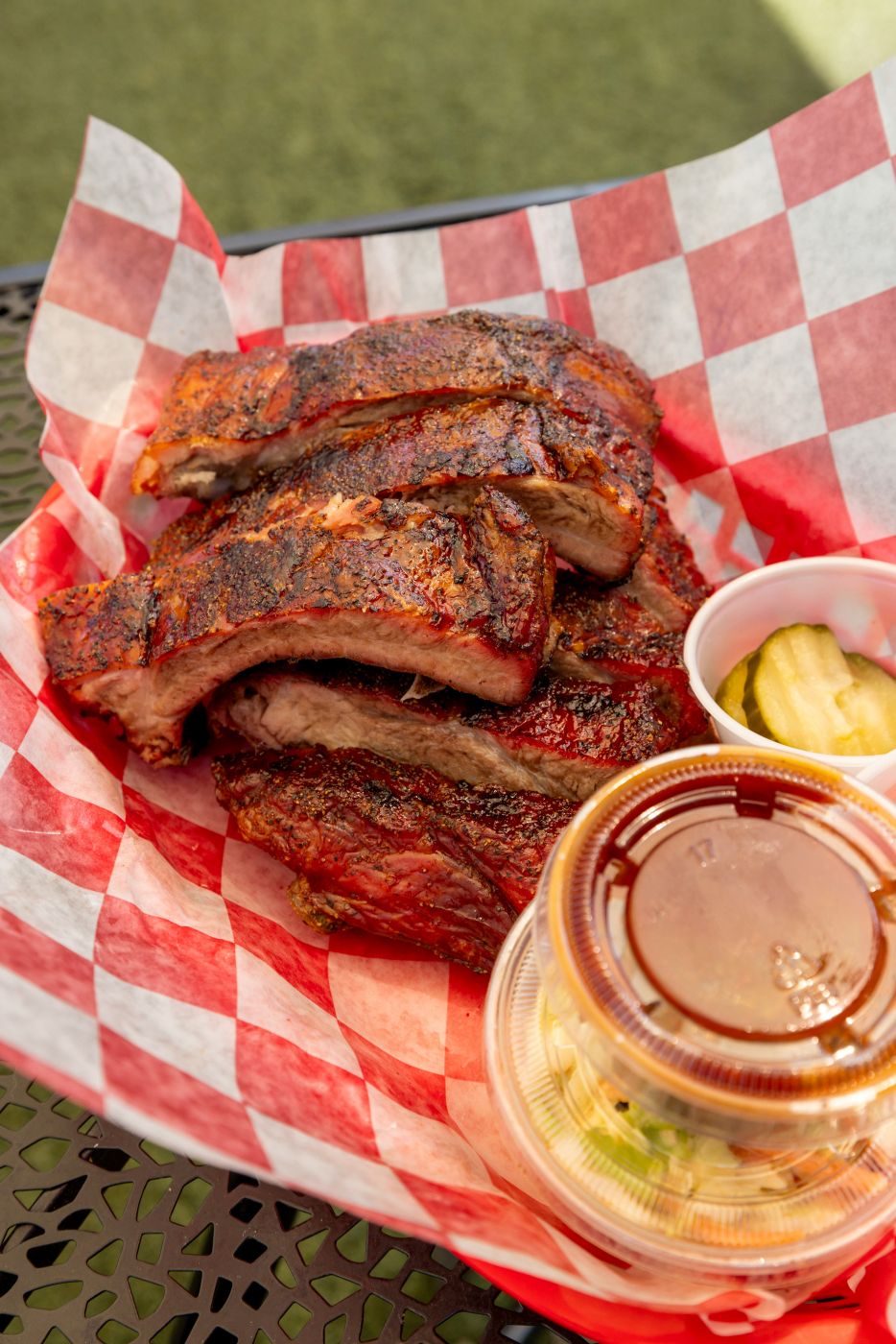 A pile of BBQ ribs, coleslaw and pickles