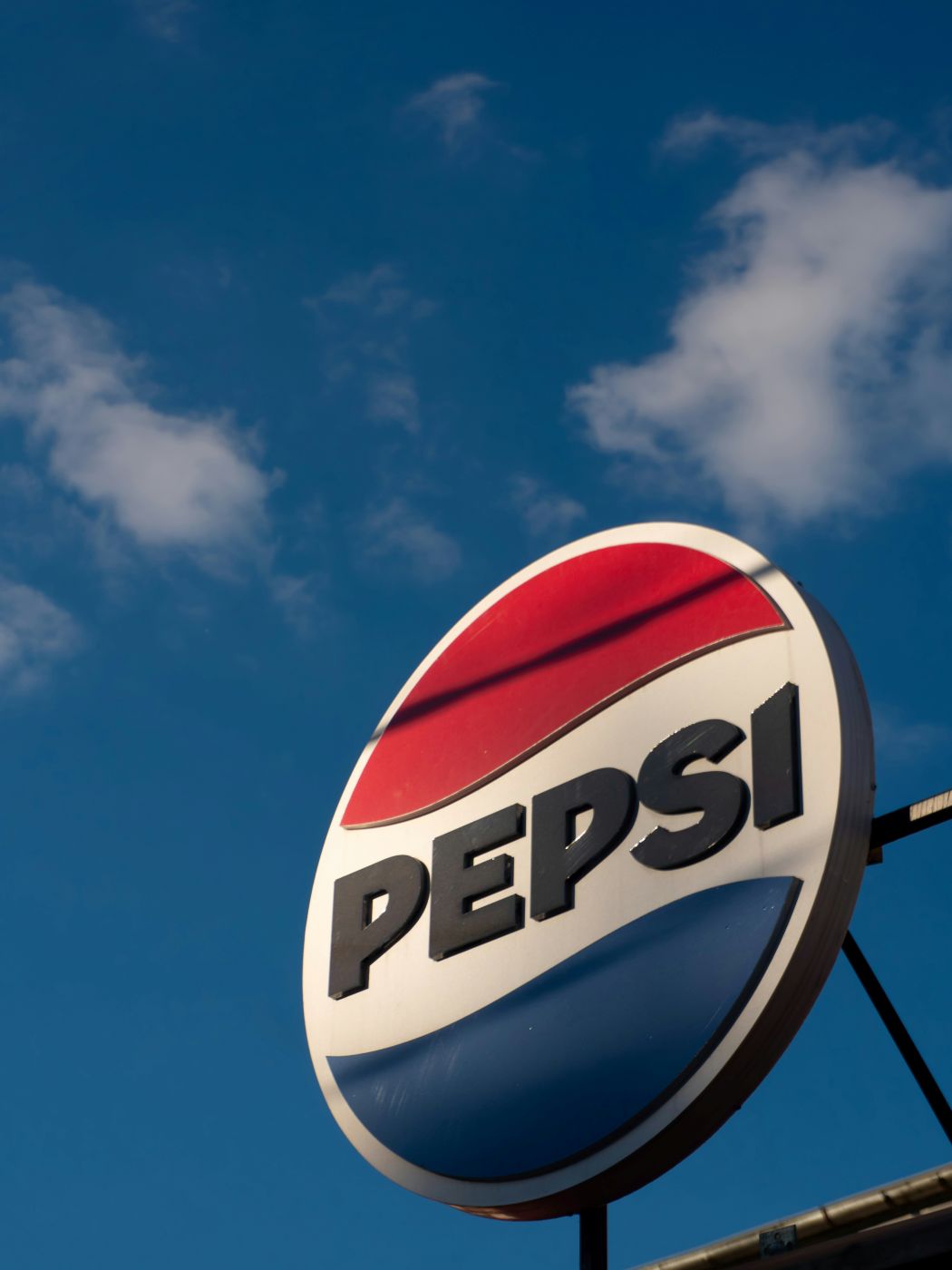 a circular Pepsi sign against a blue sky